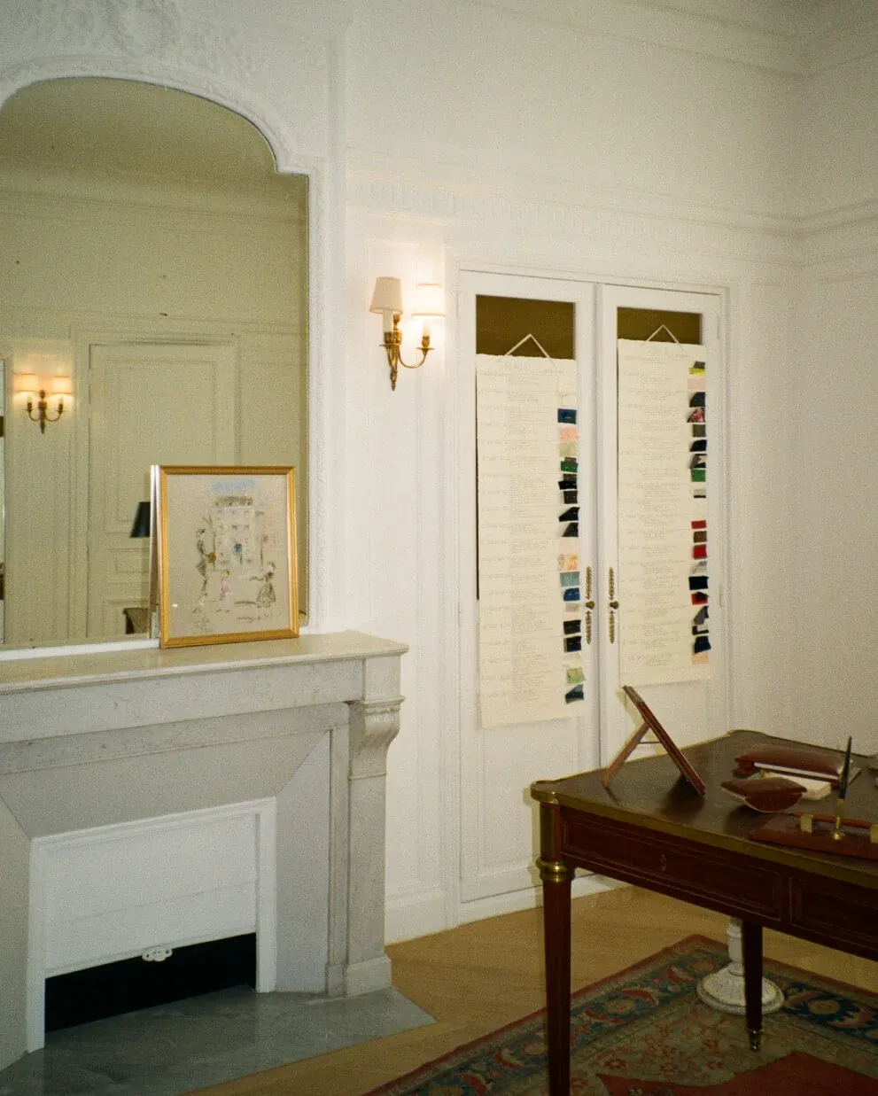 Elegant room with white marble fireplace, large mirror, and traditional wooden desk.