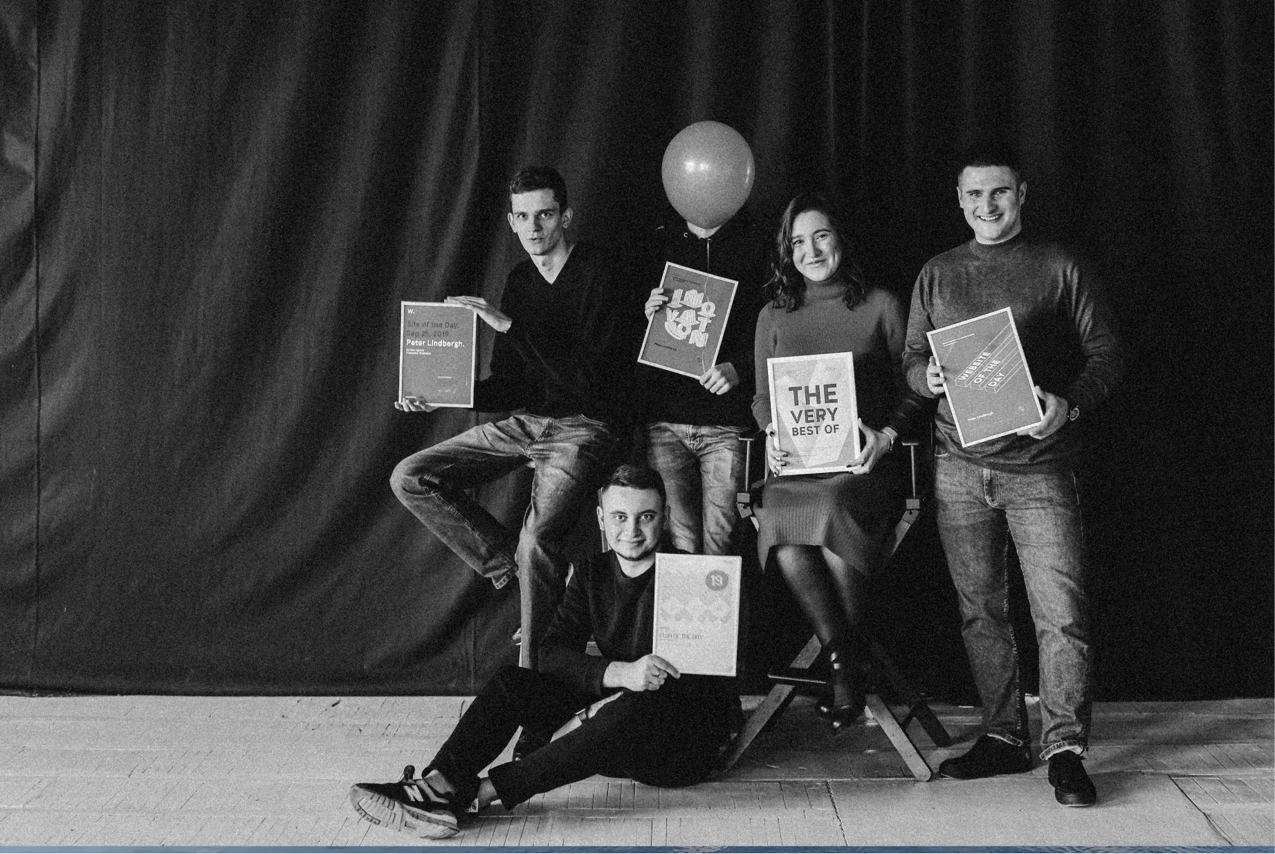 Five young adults proudly holding books and documents in a black and white portrait.