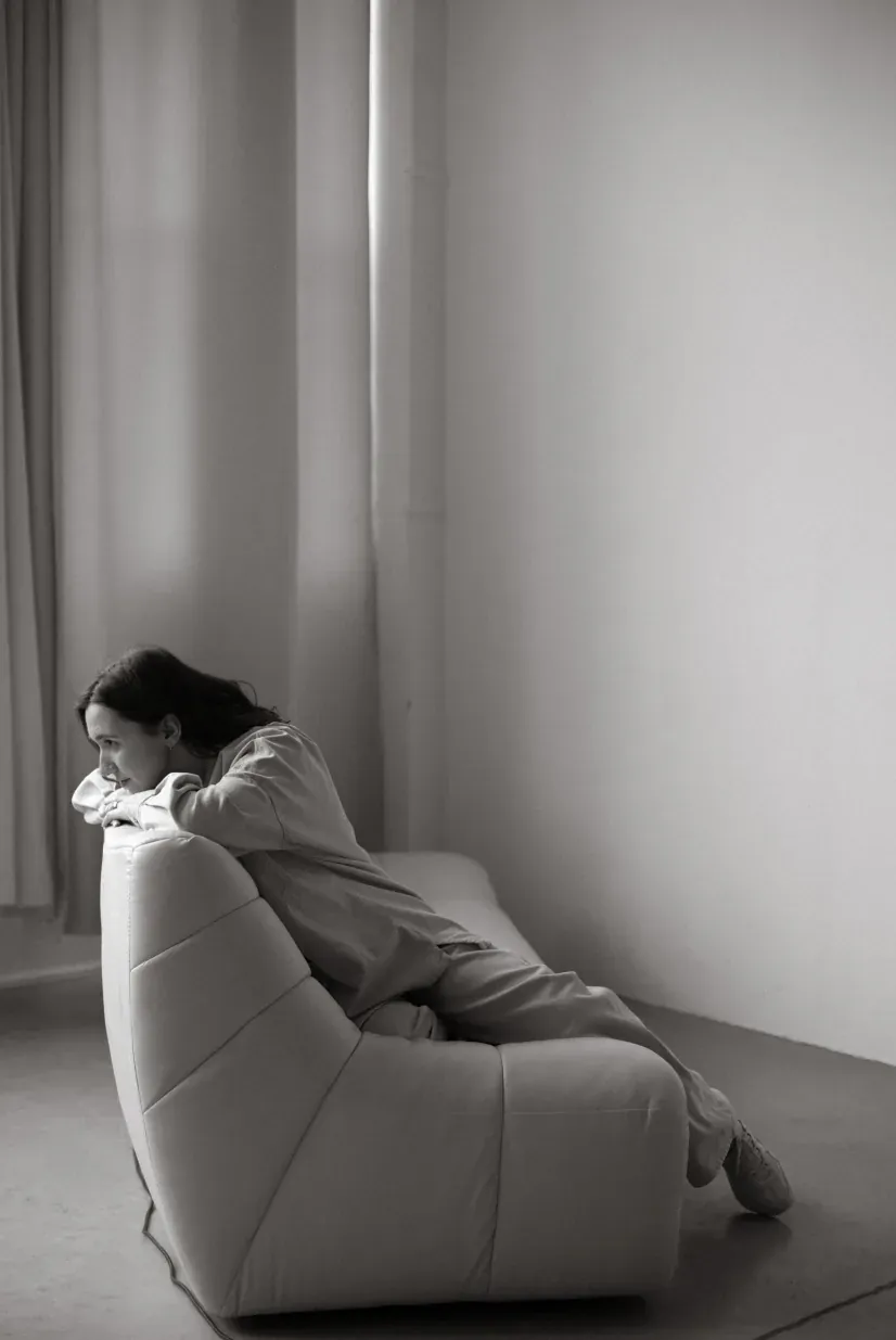 Black and white photo of a woman relaxing in a modern armchair, looking thoughtfully.
